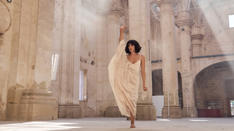 bailarina subiendo la pierna con un vestido blanco